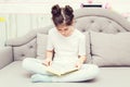 Cute caucasian teenage girl is sitting on the sofa with a book Royalty Free Stock Photo