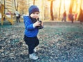 Cute caucasian toddler boy in casual clothes walking in city park holding paper cup and sipping warm drink. Adorable child having Royalty Free Stock Photo