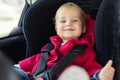 Cute caucasian toodler boy sitting in child safety seat in car during road trip. Adorable baby smiling and enjoying trip in Royalty Free Stock Photo