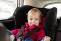 Cute caucasian toodler boy sitting in child safety seat in car during road trip. Adorable baby smiling and enjoying trip in Royalty Free Stock Photo