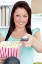 Cute caucasian woman holding a remote and popcorn Royalty Free Stock Photo
