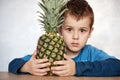 Cute Caucasian 7 year old boy with brown eyes holding a pineapple looking at the camera
