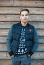 Cute charming young man with a beautiful smile with a hairstyle in a stylish jacket in a knitted New Year`s sweater in blue jeans Royalty Free Stock Photo