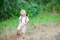 A cute cheeky small toddler boy in sunny summer nature. Copy space.