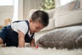 A cute, cheerful Asian baby boy is playing with toys and crawling on the floor in the living room Royalty Free Stock Photo