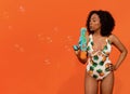 Cute young black woman in swimwear blowing water gun, copy space Royalty Free Stock Photo