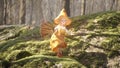 A cute cheerful elf is dancing a fiery dance on a green stone in a summer sunny forest. Fairy elven magic concept. 3D