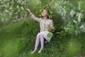 Cute cheerful girl in the flowered cherry-tree garden