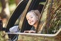Cute cheerful little caucasian girl sitting inside the car, looking out the window and smiling. Family road trip Royalty Free Stock Photo