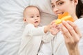 Cute cheerful mother plays with her newborn son lying in bed Royalty Free Stock Photo