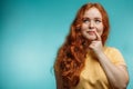 Cute cheerful redhead young girl in yellow over blue background with face. Royalty Free Stock Photo