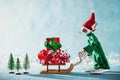 Cute Cheerful Santas Helper Elf Loading Christmas Gifts Onto Santas Sleigh. North Pole Christmas Scene. Elf at work. Royalty Free Stock Photo