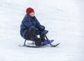 Cute, cheerful young boy in hat, blue jacket plays with snow, has fun, smiles, makes snowman in winter park. Active lifestyle Royalty Free Stock Photo