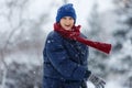 Cute, cheerful young boy in hat, blue jacket plays with snow, has fun, smiles, makes snowman in winter park. Royalty Free Stock Photo