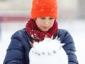 Cute, cheerful young boy in hat, blue jacket plays with snow, has fun, smiles, makes snowman in winter park. Royalty Free Stock Photo