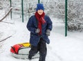 Cute, cheerful young boy in hat, blue jacket plays with snow, has fun, smiles, makes snowman in winter park. Royalty Free Stock Photo