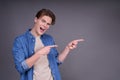 Cute cheerful young man in a denim shirt shows fingers to the side Royalty Free Stock Photo