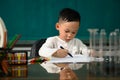 Cute child Asian boy doing homework. Clever kid drawing at desk. Schoolboy. Elementary school student drawing at workplace. Kid Royalty Free Stock Photo