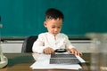 Cute child Asian boy using Magnifying glass. Clever kid drawing at desk. Schoolboy. Elementary school student drawing at workplace Royalty Free Stock Photo