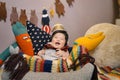 Cute child in a basket with toys, adorned with a crown