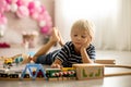 Cute child, blond toddler boy, playing with wooden trains Royalty Free Stock Photo