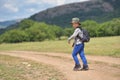 Cute child boy with backpack walking on a little path in mountains. Hiking kid Royalty Free Stock Photo