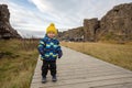 Cute child, boy, enjoying a sunny day in Waterfall in Thingvellir National Park rift valley, Iceland autumntime Royalty Free Stock Photo