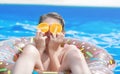 Cute child boy on funny inflatable donut float ring in swimming pool with oranges. Teenager learning to swim Royalty Free Stock Photo