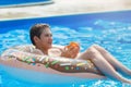 Cute child boy on funny inflatable donut float ring in swimming pool with oranges. Teenager learning to swim, have fun in outdoor Royalty Free Stock Photo