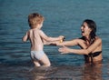 Cute child boy play with mom in sea, ocean. Mom and kid with smiling faces spend time together in sea on sunny day Royalty Free Stock Photo