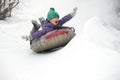 Cute Child Boy Riding On Snow Tubing Rising Hands Up. Kid Sledding Slide Down Hill. Winter Fun Activity Outdoor