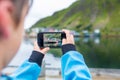 Cute child, boy, taking picture of the typical Rourbuer fishing cabins in Lofoten village on a rainy day, summertime