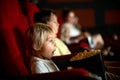 Cute child, boy, watching movie in a cinema, eating popcorn and enjoying Royalty Free Stock Photo