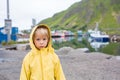 Cute child, boy, watching the typical Rourbuer fishing cabins in Lofoten village on a rainy day, summertime