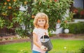 Cute child boy with watering can in the yard garden. Adorable little child helping parents to grow vegetables