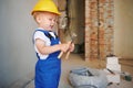 Cute child builder holding pliers at construction site.