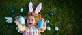 Cute child bunny wear rabbit ears in garden, Happy Easter day. Bunny boy, funny outdoor portrait. Top view funny kids