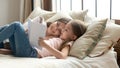 Cute child daughter holding book reading to mom in bed