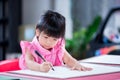 Cute child doing artwork on red desk. Asian girl drawing cartoon on paper. Happy kid learning at home. Children aged 4 years old Royalty Free Stock Photo