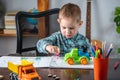 Cute child is drawing with pencils on paper in an album at the table. Preschool education and development of creativity Royalty Free Stock Photo