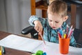 Cute child is drawing with pencils on paper in an album at the table. Preschool education and development of creativity Royalty Free Stock Photo