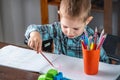 Cute child is drawing with pencils on paper in an album at the table. Preschool education and development of creativity Royalty Free Stock Photo