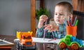 Cute child is drawing with pencils on paper in an album at the table. Preschool education and development of creativity Royalty Free Stock Photo