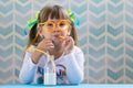 Cute child drinking milk with funny glasses straw. Growing up