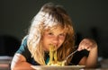 Cute child eating breakfast at home. Cute little kid eating spaghetti pasta at home. Close up portrait of funny kid Royalty Free Stock Photo
