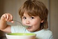 Cute child eating breakfast at home. Parenthood. Baby eating. Young kid sitting on the table eating with funny Royalty Free Stock Photo