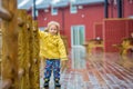 Cute child, enjoying little fishing village with rorbuer cabins on a heavy rainy day