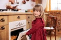 Cute child enjoys homemade cupcakes in stove. Little girl child waiting for baking Xmas cookies. Daughter cook in kitchen. Little Royalty Free Stock Photo