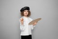 Cute child girl artist poses in studio holds a paint brush and palette. Children hobby concept Royalty Free Stock Photo