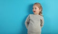 Cute child girl in astonishment looks to the side on  blue background Royalty Free Stock Photo